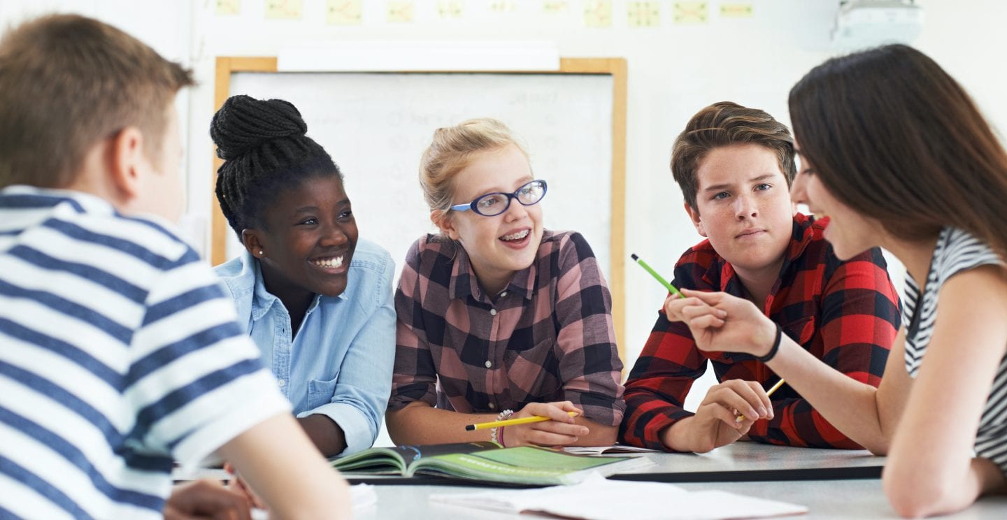 Students seated in a group discuss an assignment.